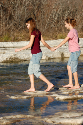 Girl leading girl scross river symbolising leadership