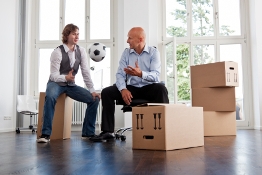 Two entrepreneurs sitting on boxes and batting a football as they prepare to start a new venture.