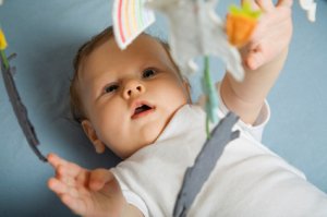 Baby in crib reaching out to mobile symbolising how endlessly curious babies and children are.